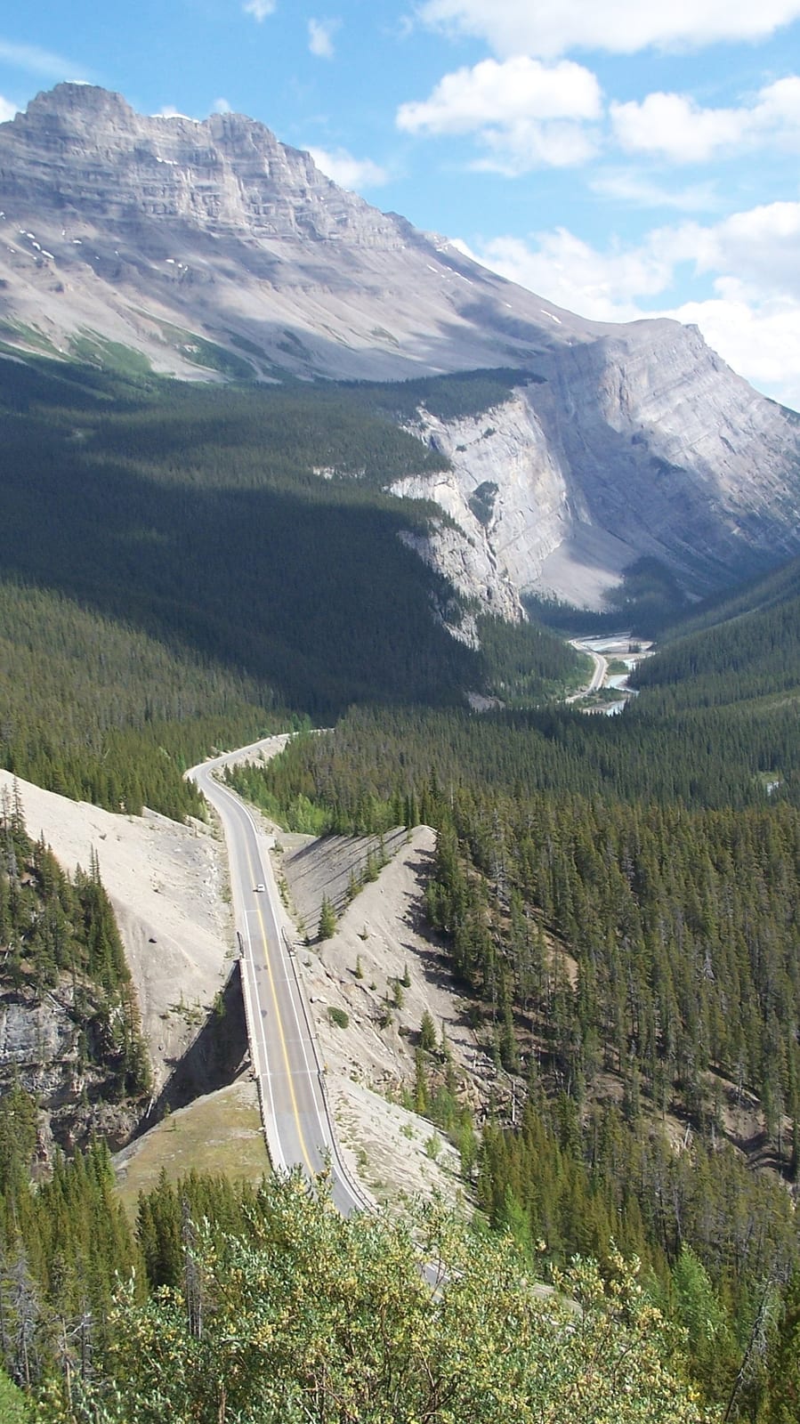 Icefields Parkway. The road winding through the valley, beneath towering rock walls.
