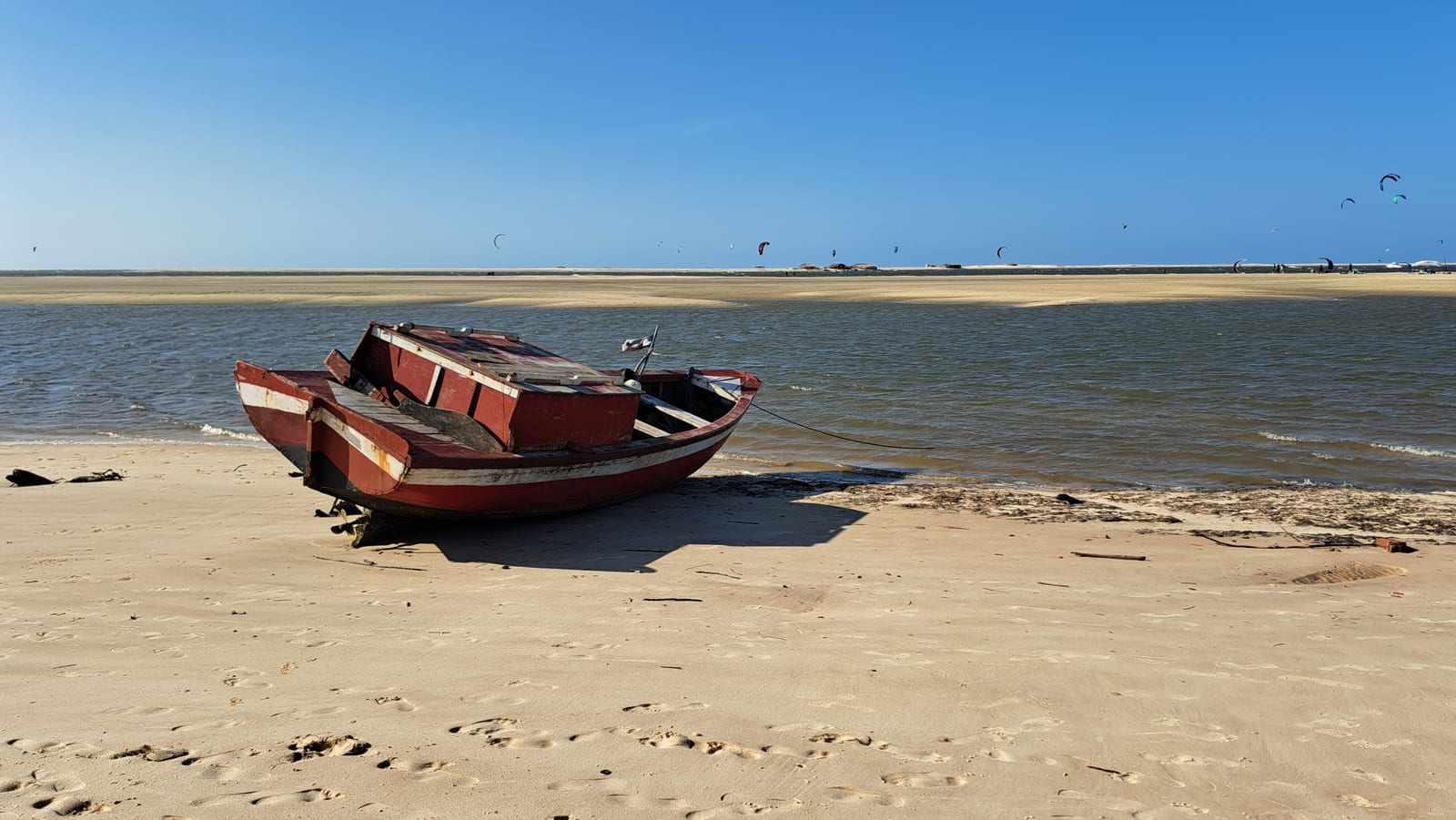 A fishing boat on the Atins beach, with kitesurfers in the background