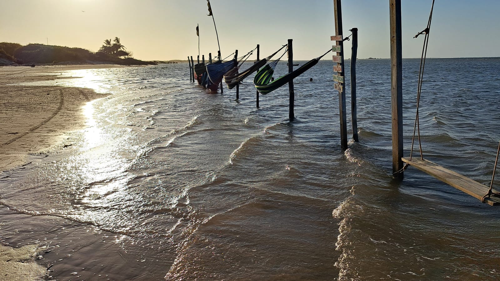 Hammocks strung over the water, on the Atins beach at sunset