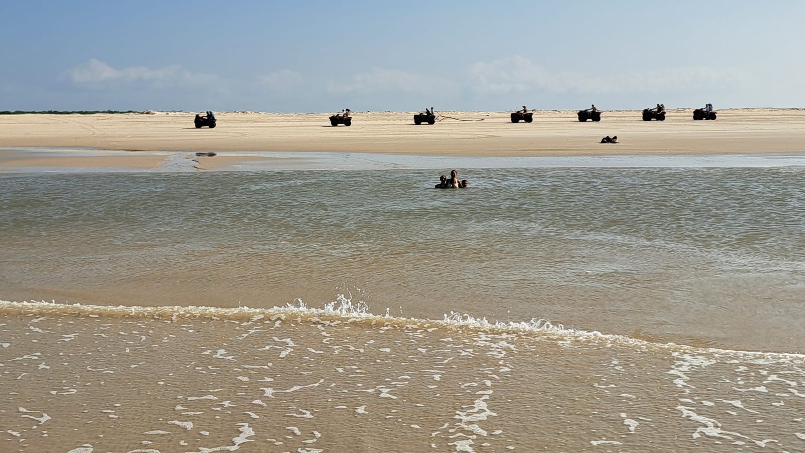 The natural low-tide pools, with swimmers and arriving quad bikes