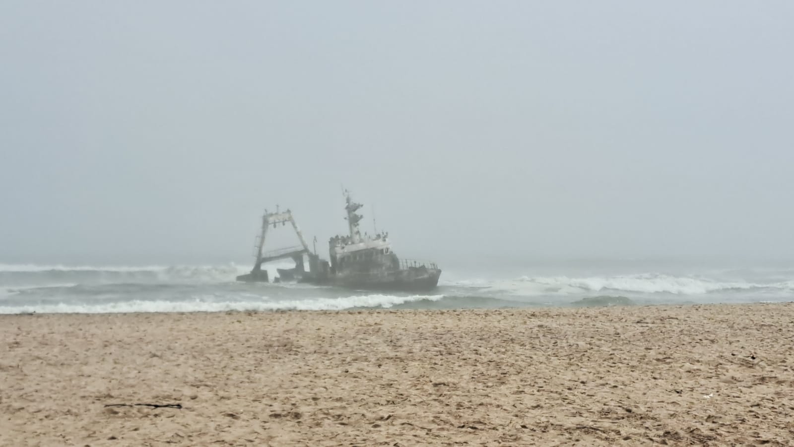Skeleton Coast — a shipwreck in the fog, the surf breaking around the hull