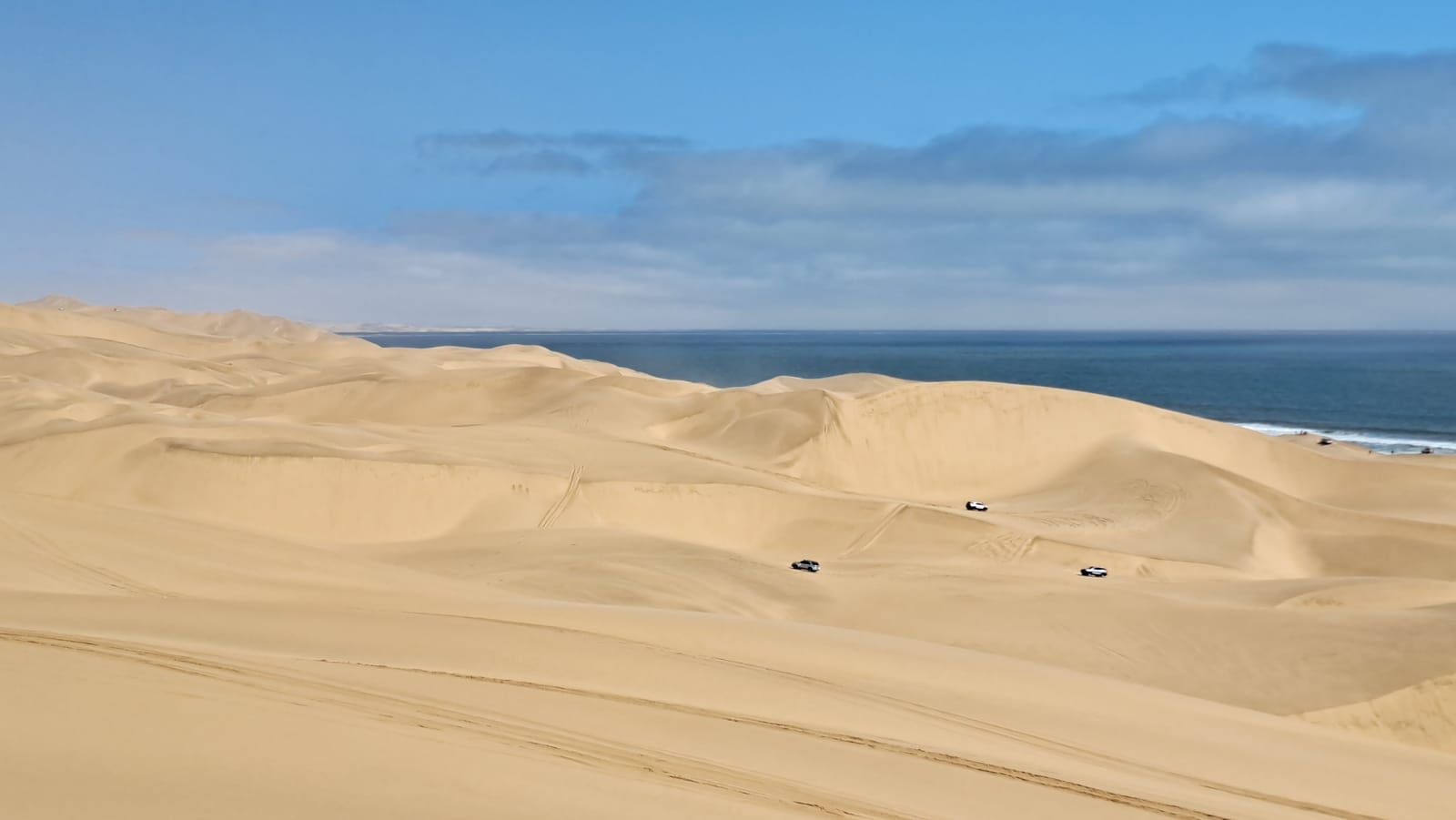 Sandwich Harbour — 4×4s on the dune crests, the Atlantic directly below